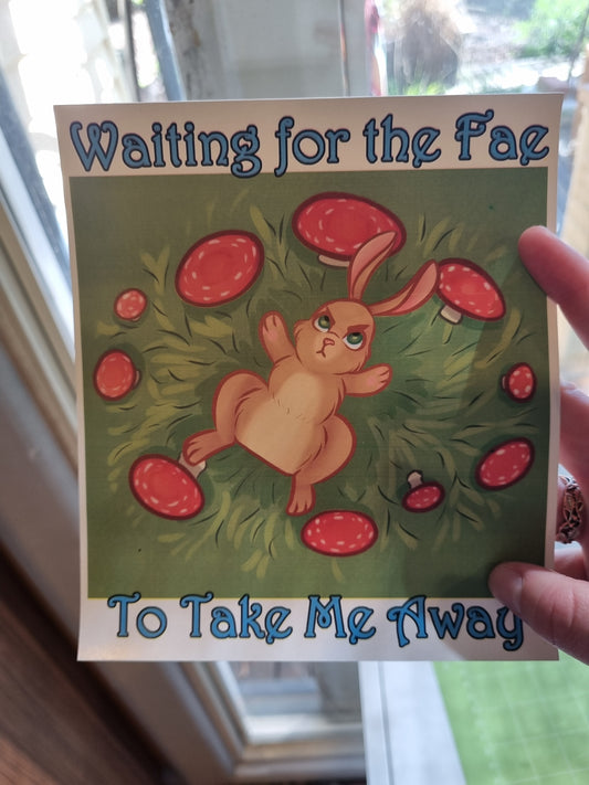 Card with a bunny and mushrooms design held by a hand in front of a window.